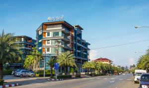 奥南海滩AVA SEA Resort Krabi, Ao Nang Beach的棕榈树城市街道上的一座高楼