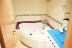 拉科鲁尼亚克瑞丝绦2号酒店的浴室设有白色浴缸,配有蓝色水槽