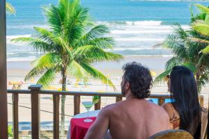 瓜鲁雅Strand Hotel Guarujá Frente Mar的坐在海滩上阳台的男人和女人