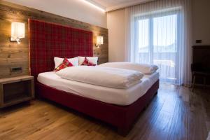 拉纳Hotel Garni Vigilhof的一间卧室配有一张大床和红色床头板