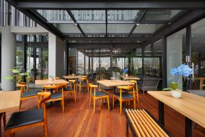 芝卡朗BATIQA Hotel Jababeka Cikarang的餐厅设有木桌、椅子和窗户。