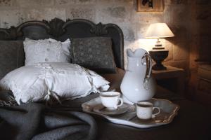 法萨诺Masseriola Antiche Fogge的一张带两个杯子和一个花瓶的托盘的床