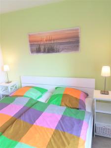 奈斯玛兹埃勒Ferienwohnung Krabbentaucher 2的卧室内一张带五颜六色棉被的床