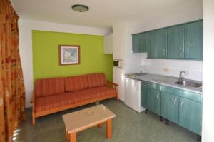 英格兰海滩绿色公园公寓酒店的客厅设有红色沙发,位于厨房内
