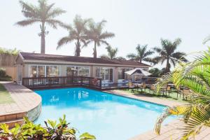 Umtentweni树下酒店及会议中心的棕榈树屋前的游泳池