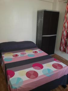 马尼拉马卡蒂经济一室公寓的一间卧室配有一张带彩色毯子的床