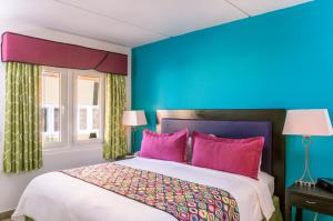 棕榈滩MVC鹰湾酒店的卧室拥有蓝色的墙壁,配有一张带粉红色枕头的床。