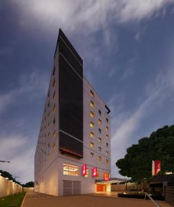 哥印拜陀ibis Coimbatore City Centre - An Accor Brand的一座高大的白色建筑,上面有红色标志