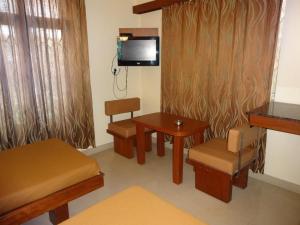 班加罗尔西塔尔住宿酒店的配有桌椅和电视的客房