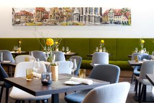 萨勒河畔瑙姆堡Gasthof Zufriedenheit的餐厅设有桌椅,墙上挂有绘画作品