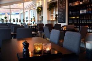 尼雪平克拉丽奥科姆潘尼尔特连锁酒店的餐厅设有木桌和带蜡烛的椅子