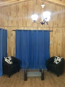 奇廉Cabañas Alto Nativo的一间设有两把椅子和蓝色窗帘的房间
