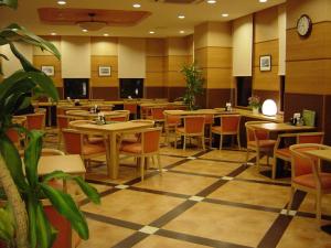 大洲Hotel Route-Inn Aso Kumamoto Airport Ekimae的餐厅设有桌椅和墙上的时钟