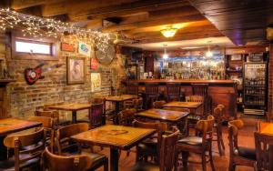 奥古斯塔Olde Town Inn的一间带木桌椅的餐厅和一间酒吧