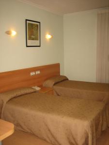 埃尔切马德鲁加酒店的酒店客房设有两张床和一张桌子。