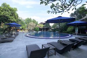 勒吉安玛塔哈利小屋酒店的一个带蓝伞和椅子的游泳池和一个游泳池