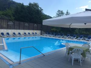 莱维科特尔梅斯卡拉诺酒店的一个带椅子和桌子的游泳池以及一把遮阳伞