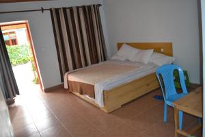 基加利Wailers Lodge的一间卧室配有一张床、一张桌子和一把蓝椅