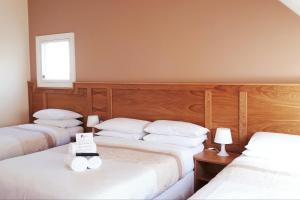 班多伦邦克之家宾馆的一间卧室设有三张床、白色床单和窗户
