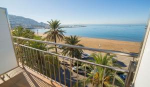 罗萨斯雷瑟奇酒店的享有海滩和棕榈树景致的阳台