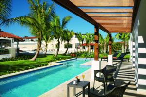 巴亚希贝Dreams Dominicus La Romana Resort & Spa的房屋旁的游泳池配有桌椅