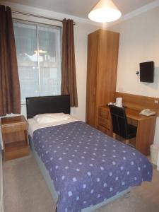 泰晤士河畔金斯顿华威旅舍的一间卧室配有一张床、一张书桌和一个窗户。