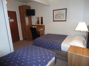 泰晤士河畔金斯顿华威旅舍的酒店客房配有一张床和一张带台灯的书桌