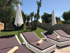 滨海波利尼亚诺Carone Suite-Charme&Pool by Bluette的一排躺椅和一把遮阳伞