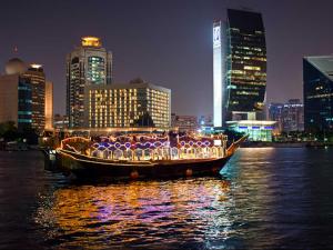 迪拜阿拉伯庭院水疗酒店的城市水面上充满灯光的船只