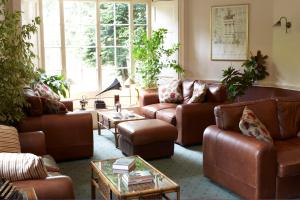 拉伊Flackley Ash Country House Hotel的客厅配有棕色皮沙发和桌子