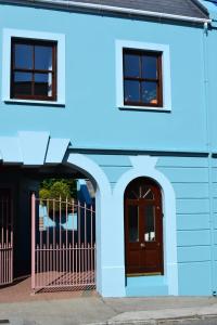 丁格尔Dingle Townhouse的蓝色的建筑,设有门和两扇窗户