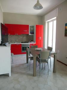 特拉尼La Casa degli Artisti的厨房配有红色橱柜和木桌及椅子