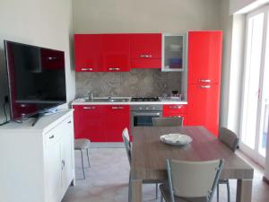 特拉尼La Casa degli Artisti的一间厨房,配有红色橱柜和一张桌子及一台电视