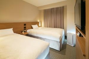 北上市JR-East Hotel Mets Kitakami的酒店客房设有两张床和一台平面电视。
