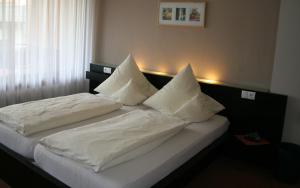 罗斯巴赫祖尔邮政酒店-餐厅的一间卧室配有两张带白色床单和枕头的床。