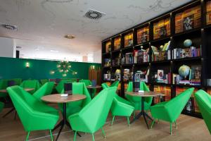 巴塞罗那万基比特酒店的一间设有绿色椅子和桌子及书架的餐厅
