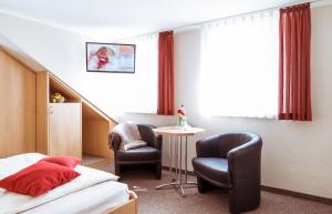 库罗阿尔滕堡Pension Hotel Sartor的配有一张床和一把椅子的酒店客房