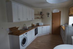 库雷萨雷Pargi Apartment的厨房配有白色橱柜、洗衣机和烘干机