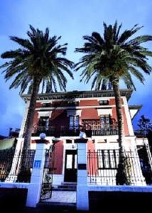 努埃瓦德兰斯Hotel Casa de Indianos Don Tomás的两棵棕榈树,在一座建筑前