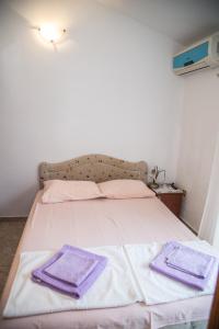 佩特罗瓦纳莫鲁Apartmani Ksenija的一间卧室配有一张带紫色毛巾的床