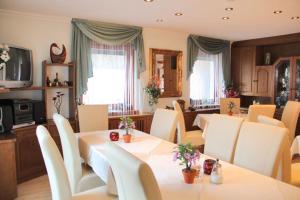 法克湖Pension Duregger的一间带桌子和白色椅子的用餐室