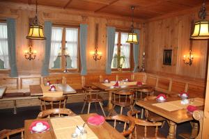 贡岑豪森Posthotel Arnold的餐厅设有木桌、椅子和窗户。