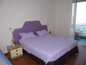 伊斯基亚Casa Antonio的一间卧室配有一张大床和紫色床头板