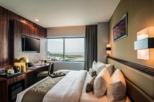 马卡萨Arthama Hotels Makassar的酒店客房配有一张床、一张书桌和一台电视。