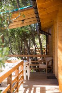 卡沃Elbadoc Camping Village的小屋的门廊配有椅子和桌子