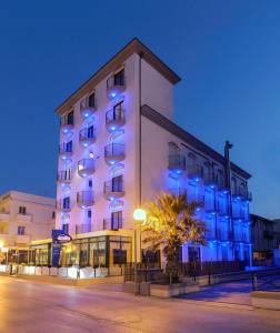 里米尼艾米利亚酒店的一座白色的大建筑,上面有蓝色的灯光