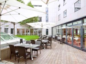 杜塞尔多夫voco Dusseldorf Seestern, an IHG Hotel的一个带桌椅和遮阳伞的户外庭院。
