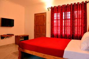 JamburRiver Near Coorg的一间卧室设有红色的床和窗户。