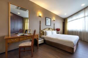 新加坡远东酒店之远东广场公寓的一间卧室配有一张床、一张书桌和一面镜子