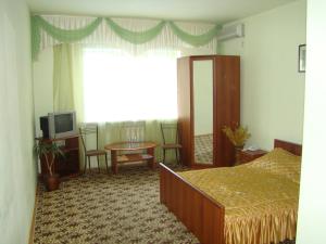 克拉斯诺达尔Отель ИРОН 1的一间卧室配有一张床、一张桌子和一个窗户。